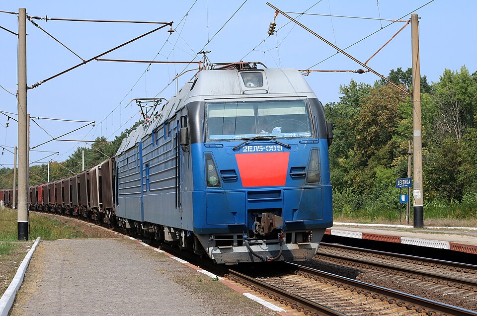 A Ukrainian Railways 2EL5 electric locomotive hauling a freight train through a halt